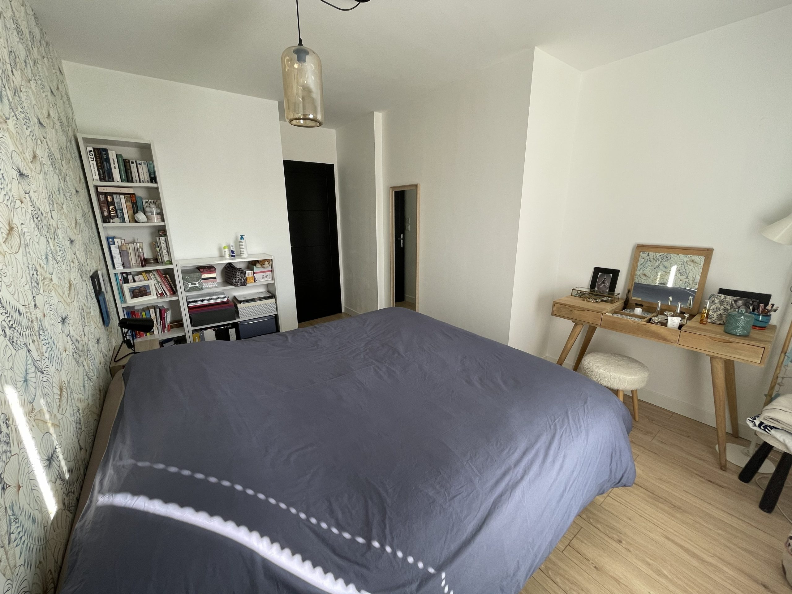 Chambre parentale avant rénovation à Coëx en Vendée, projet Albizia avec coiffeuse en bois et papier peint feuillage existant